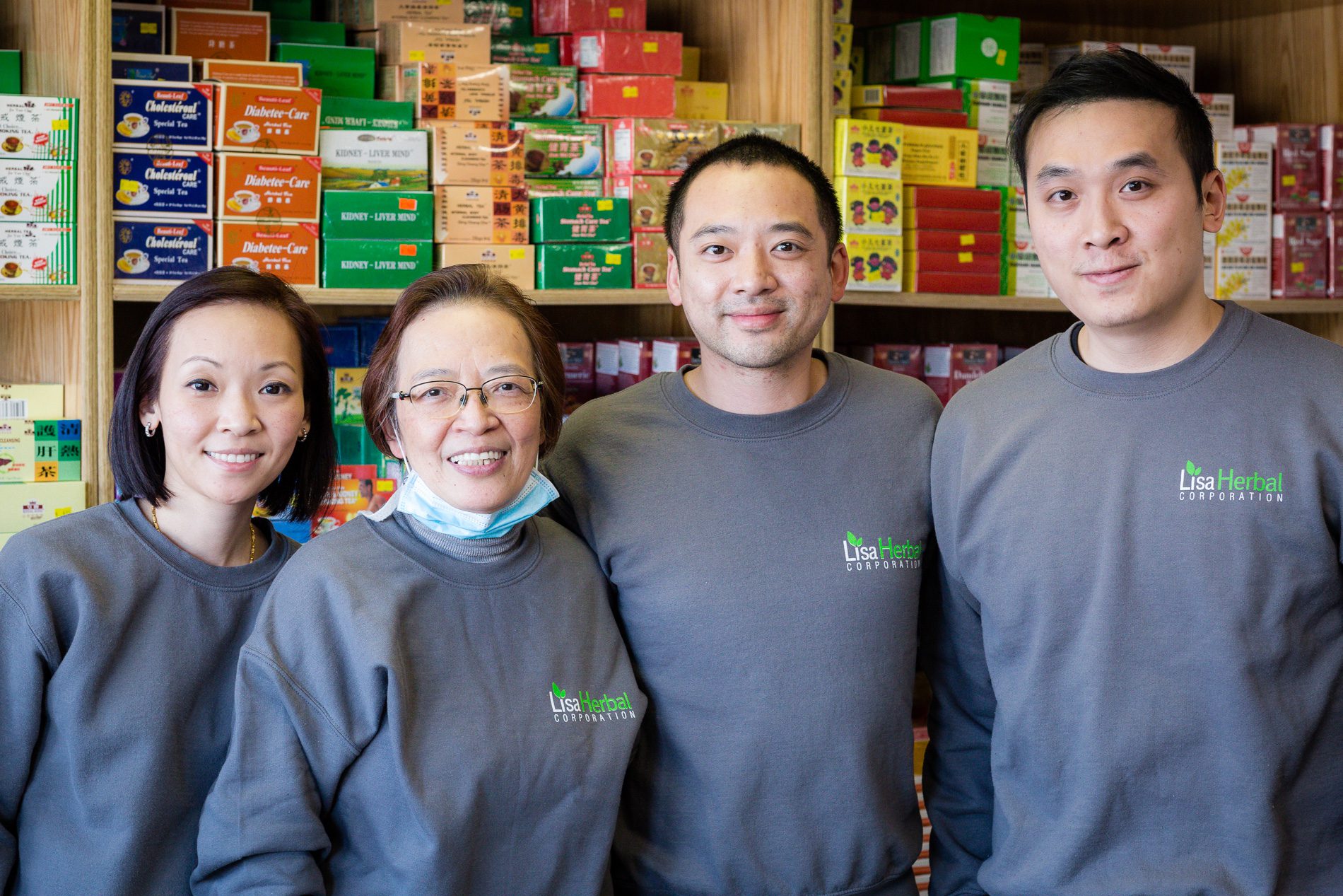 Lisa Lau and her children in front of a wall of tea boxes