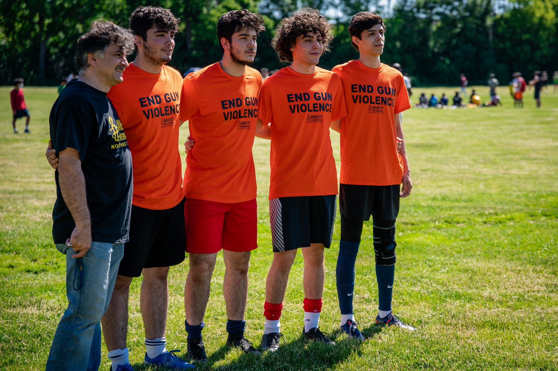 four soccer players wearing orange shirts that read"end fun violence"