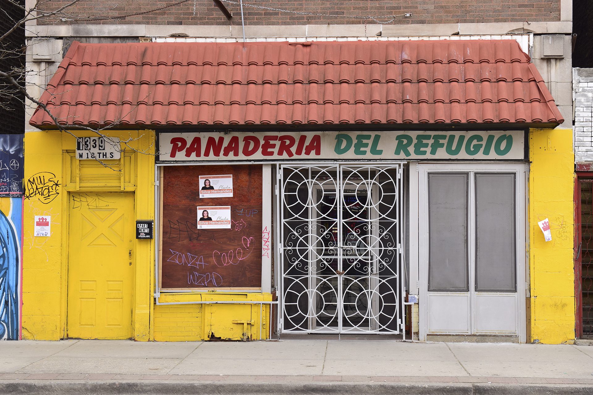 building of panaderia del refugio with white and yellow paint and shuttered, some graffiti