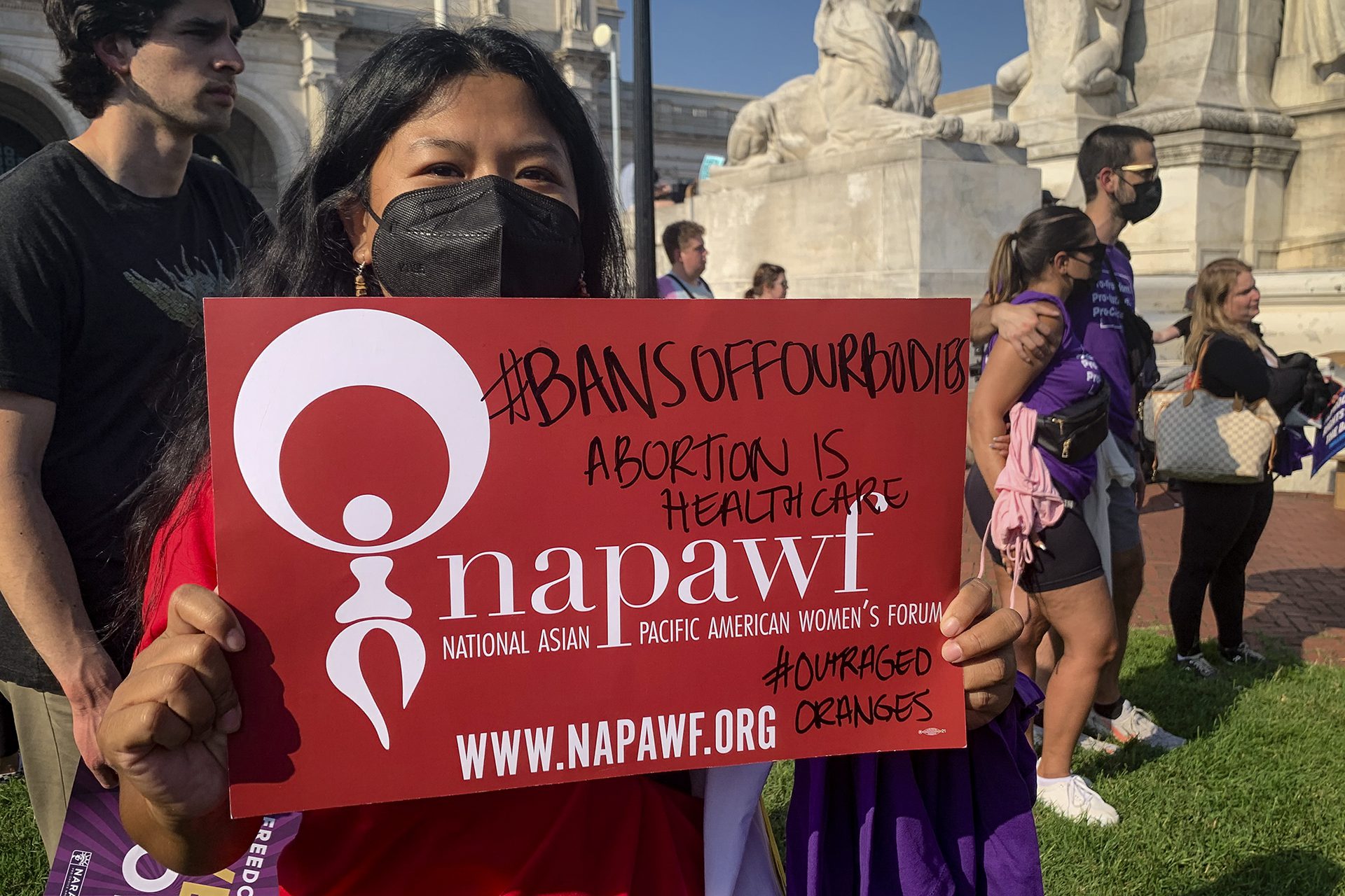 May Thach tient une pancarte rouge sur laquelle on peut lire &quot;#bansoffourbodies&quot; &quot;abortion is heathcare&quot; &quot;napawf&quot;.