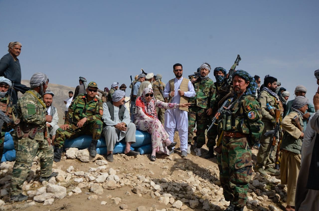 Salima Mazari in a pink flowered dress surrounded by soldiers on the frontlines