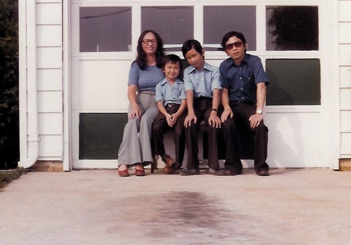Viet Thanh Nguyen, left center, and from left his mother, Linda Kim Nguyen, brother, Tung Thanh Nguyen and father, Joseph Thanh Nguyen in front of a white garage door in 1976