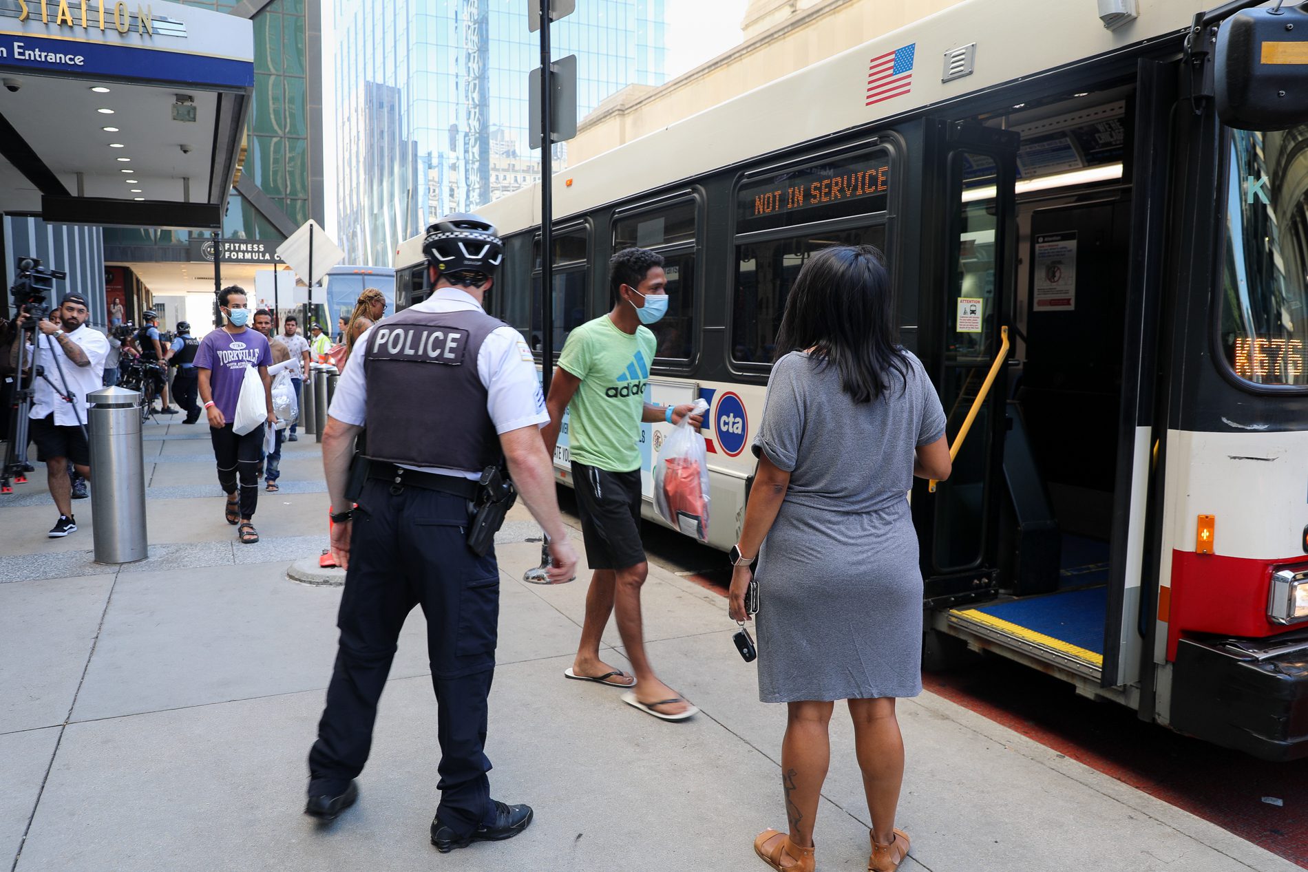 Los migrantes caminan hacia un autobús urbano tras ser enviados a Chicago desde Texas por el gobernador Greg Abbott