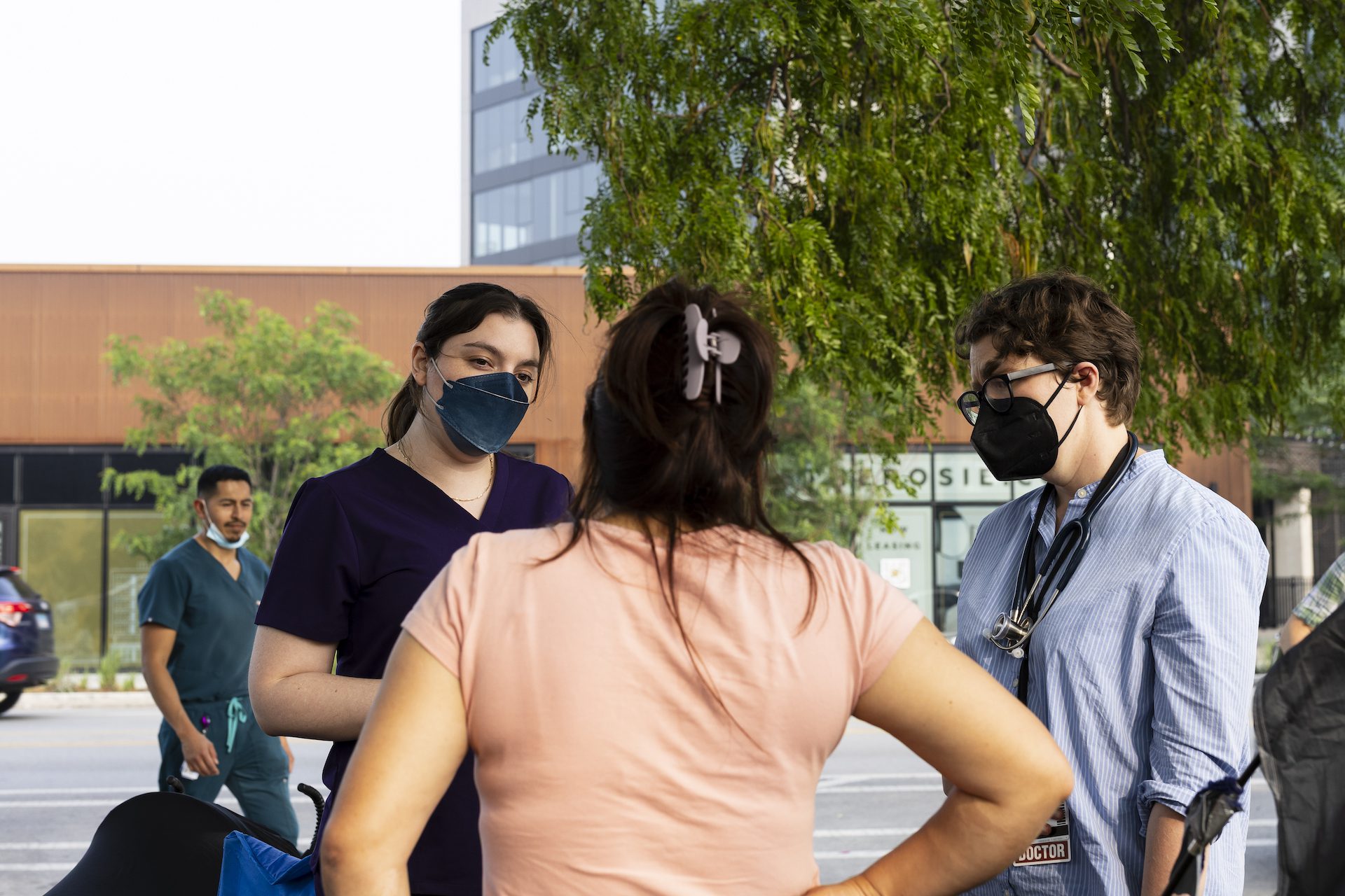 Estudiantes de medicina y médicos enmascarados hablan con una mujer a las puertas de una comisaría.