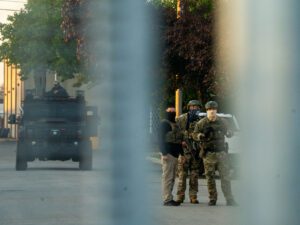 Tres agentes federales enmascarados detrás de la valla perimetral de un centro de detención.
