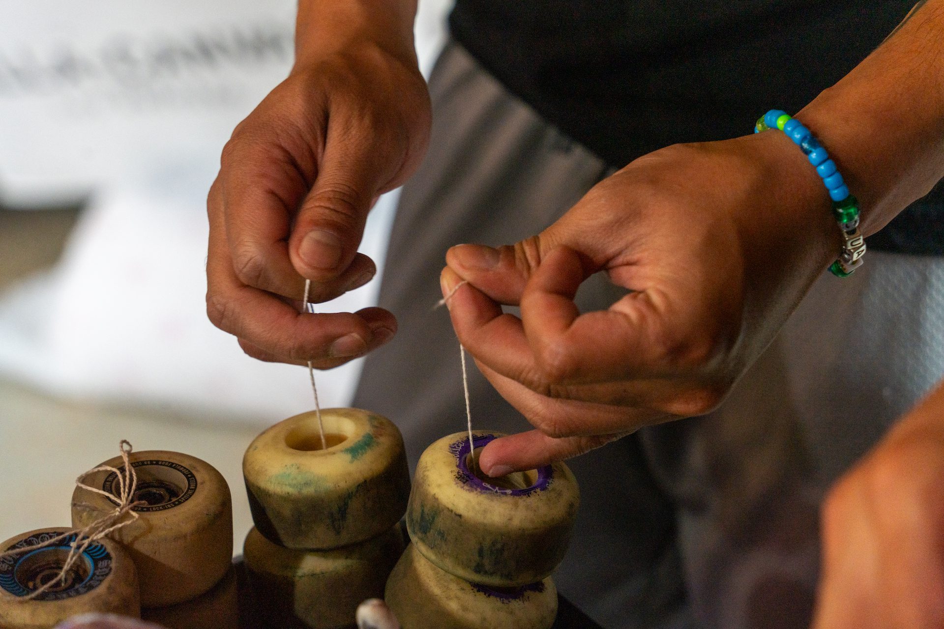 A close up photos of Javier Ponce attaching skateboard wheels with string to transport to Guatemala.