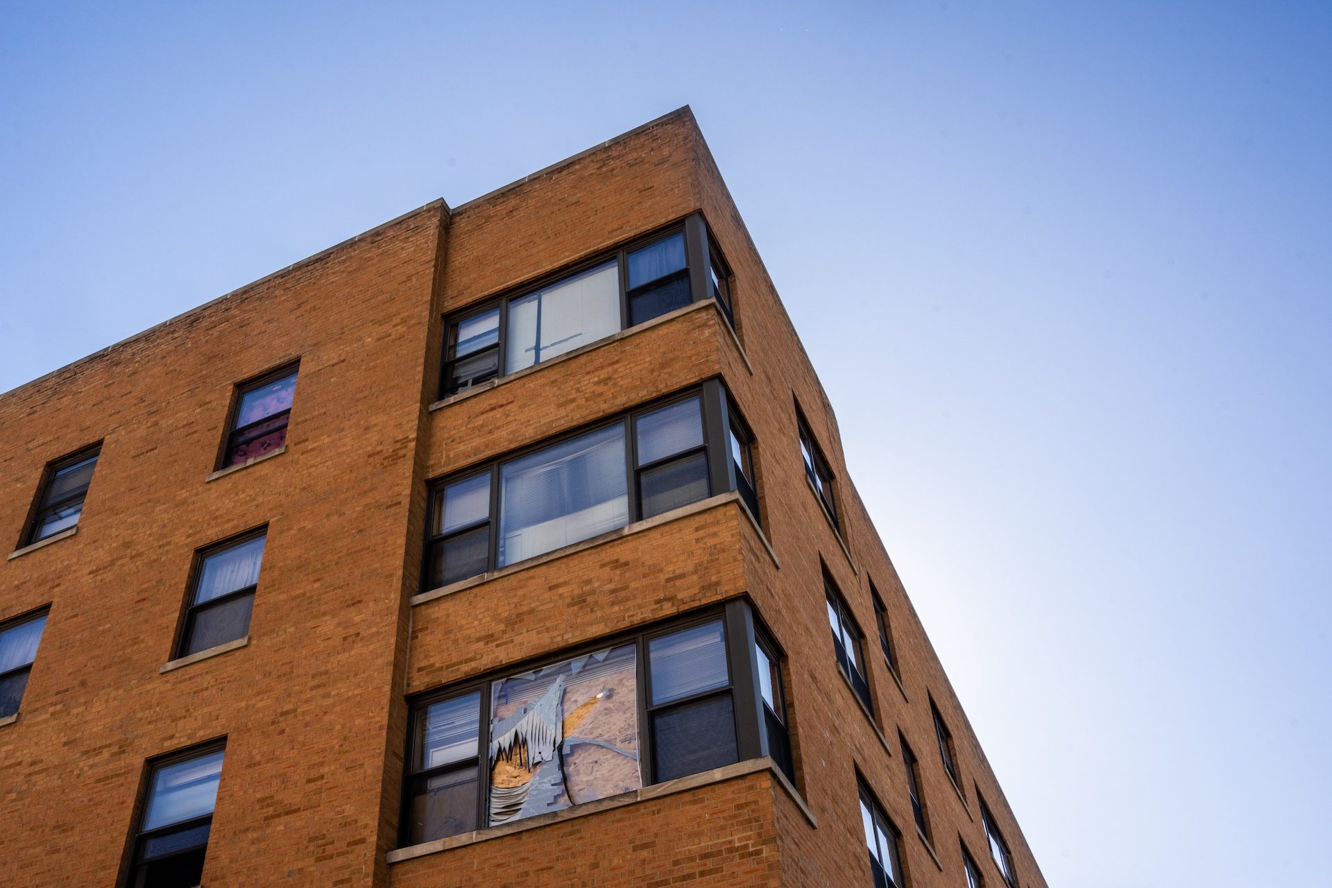 The corner of a multi-story apartment building is seen with broken, boarded-up windows. The South Shore apartment building was raided on Sept. 30 in the middle of the night by multiple federal agencies.