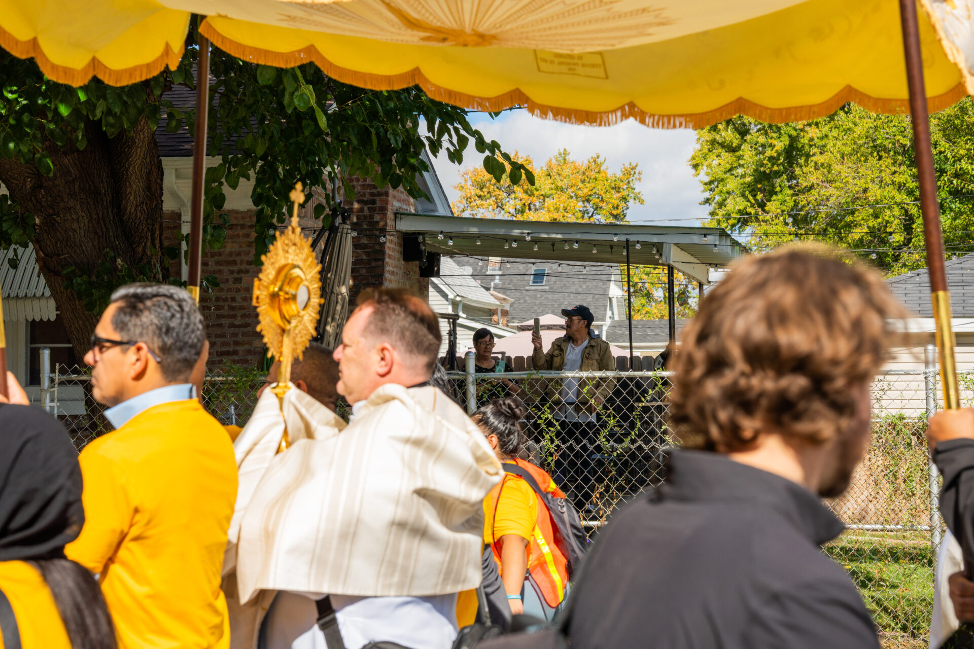 Broadview residents on their back porch record the Eupharistic Procession organized by the Coalition for Spiritual and Public Leadership (CSPL) as they walk to the Broadview ICE processing center on Oct. 11, 2025.