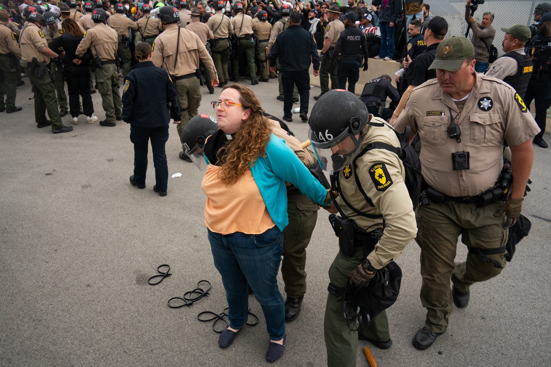 Wrist restraints are put on Rev. Hannah Kardon as she is detained by a group of Illinois State Police while protesting on Beach Street Oct. 17, 2025.
