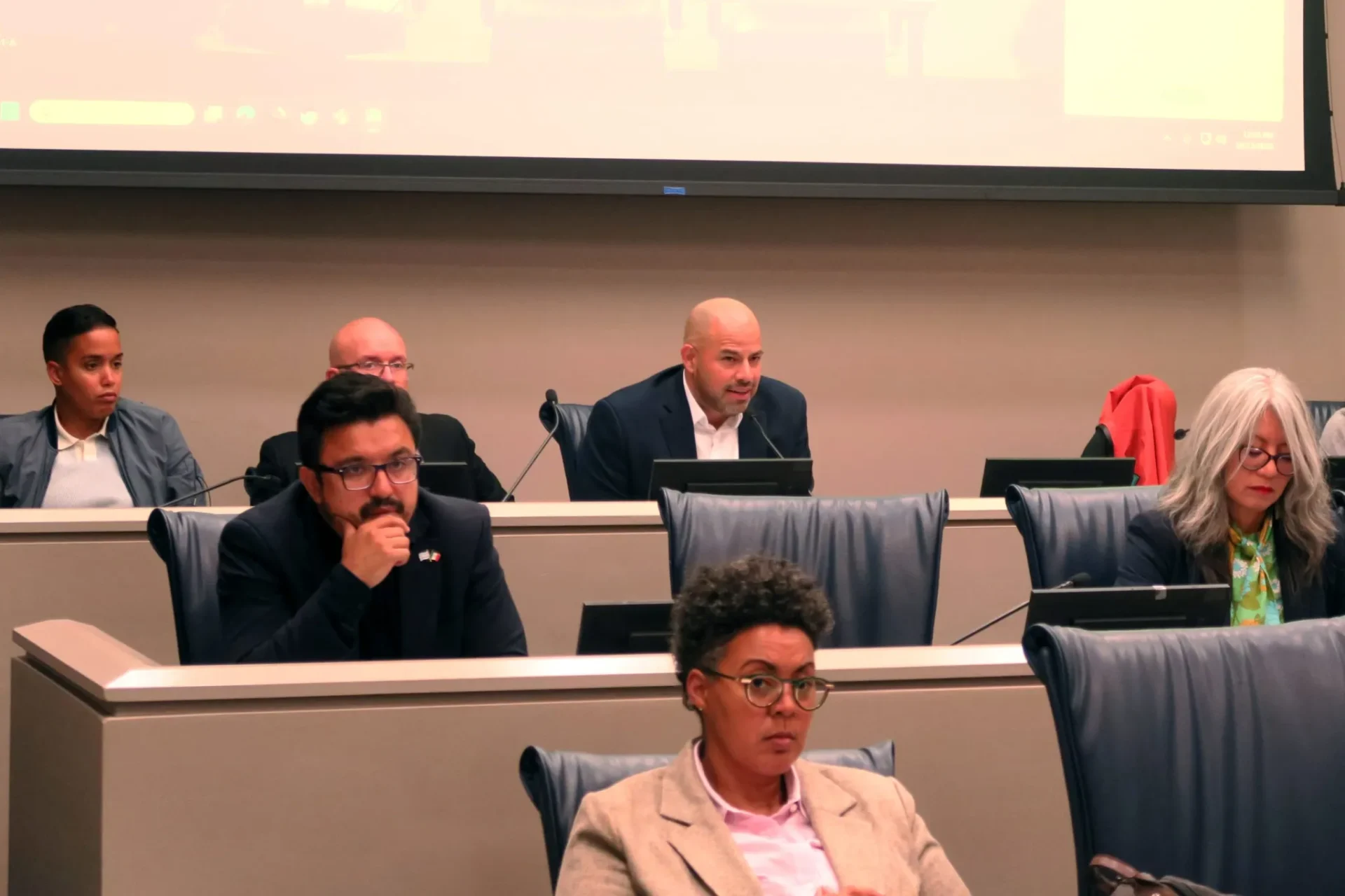 Ald. Andre Vasquez (40th) speaks into a microphone, surrounded by several other alder people, during an Oct. 15, 2025 hearing of the City Council’s Committee on Immigrant and Refugee Rights.