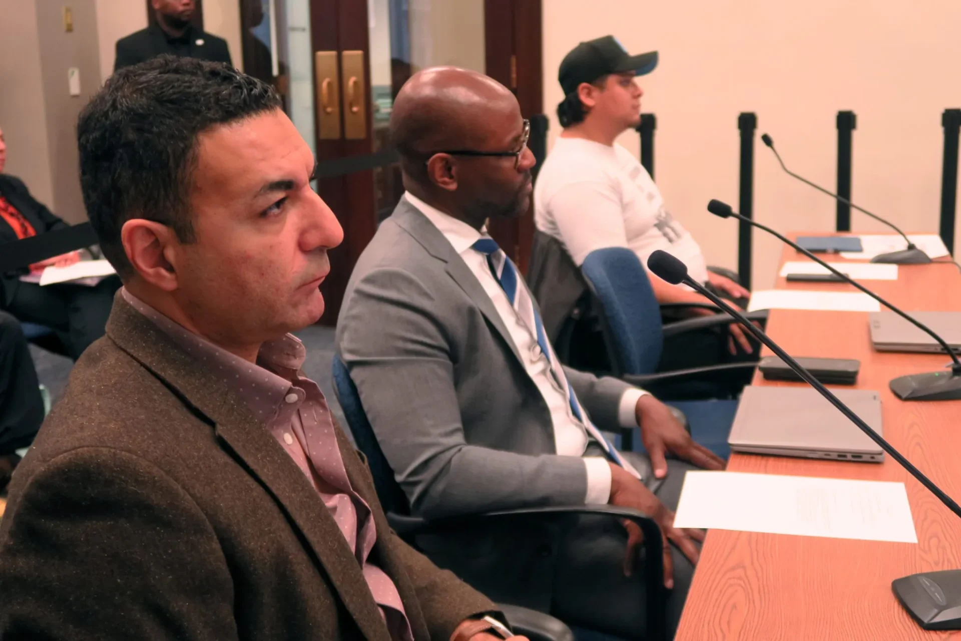 Three men, Ahmed Rehab, executive director of the Council of American Islamic Relations’ Chicago branch, Vaughn Bryant, Metropolitan Peace Initiatives’ executive director, and Geovanni Celaya, an organizer with Latino Union of Chicago attend an Oct. 15, 2025 hearing of the City Council’s Committee on Immigrant and Refugee Rights.