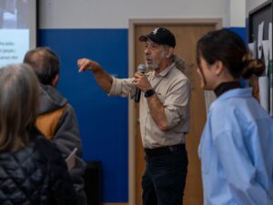 Jorge Mújica Murias, an organizer with Arise Chicago, stands in the front of a small meeting room as he walks small business owners through role play-scenarios to prepare them in case they encounter ICE officers on Oct. 21, 2025.