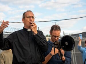 El organizador comunitario del Proyecto Resurrección y líder religioso durante muchos años, el padre Brendan Curran, habla por un megáfono mientras reúne a los manifestantes frente a las instalaciones de ICE en Broadview, Illinois, el 12 de septiembre de 2025.