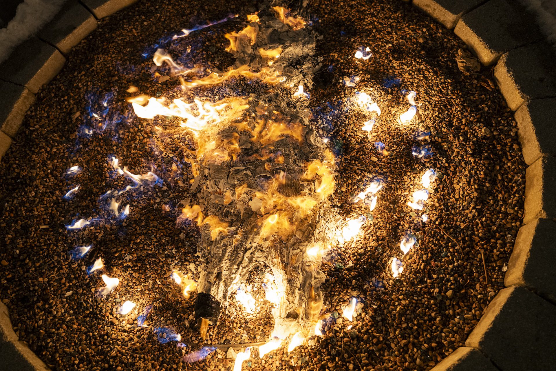 The remnants of notes left by Quema del Diablo participants burn around the ashes of the devil piñata in a circular fire pit at Park & Field.