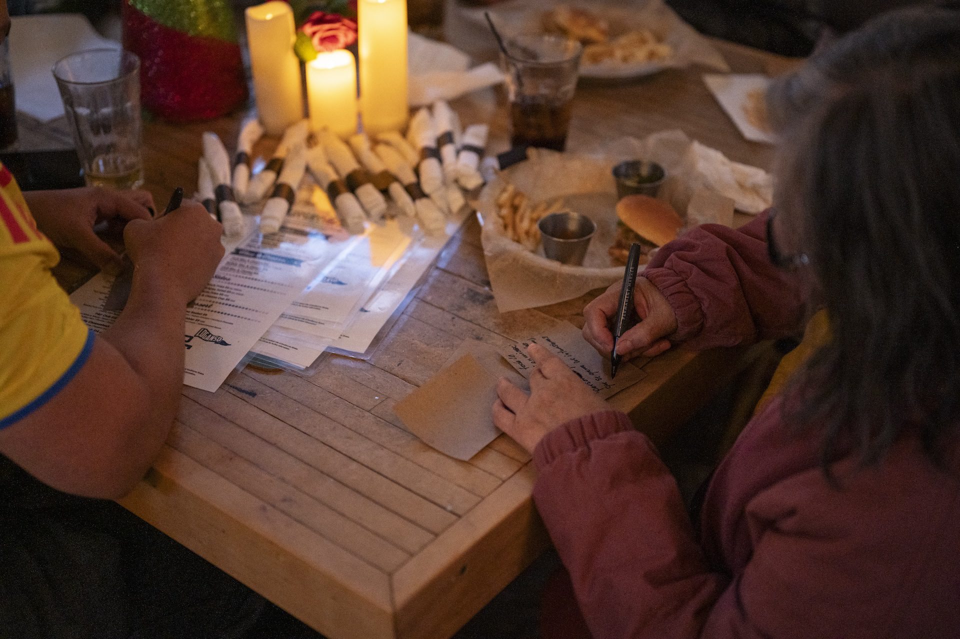 Participants at the Quema del Diablo celebration sit at a table surrounded by their meals as they write down negative experiences from 2025 before stepping outside to the fire.