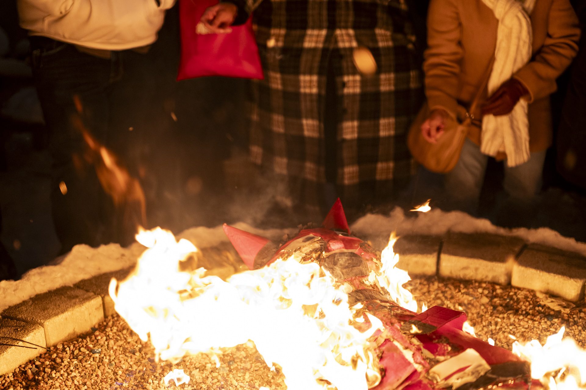 The devil piñata burns quickly in the fire pit at Park & Field as it lays on the rocks inside of the fire pit.