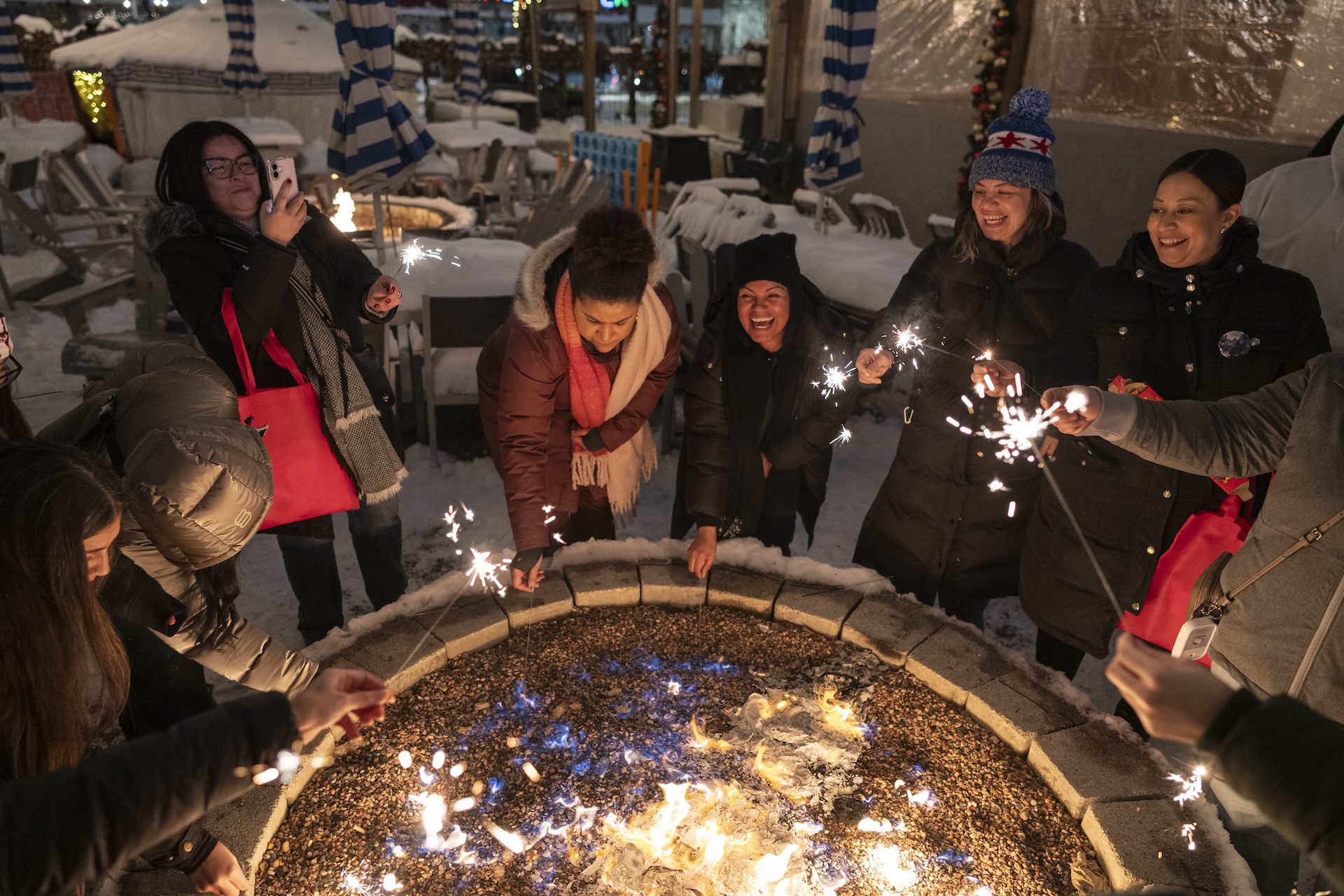 After the devil piñata burned out, a group of adults lit sparklers around the fire at Park & Field as they laugh together.