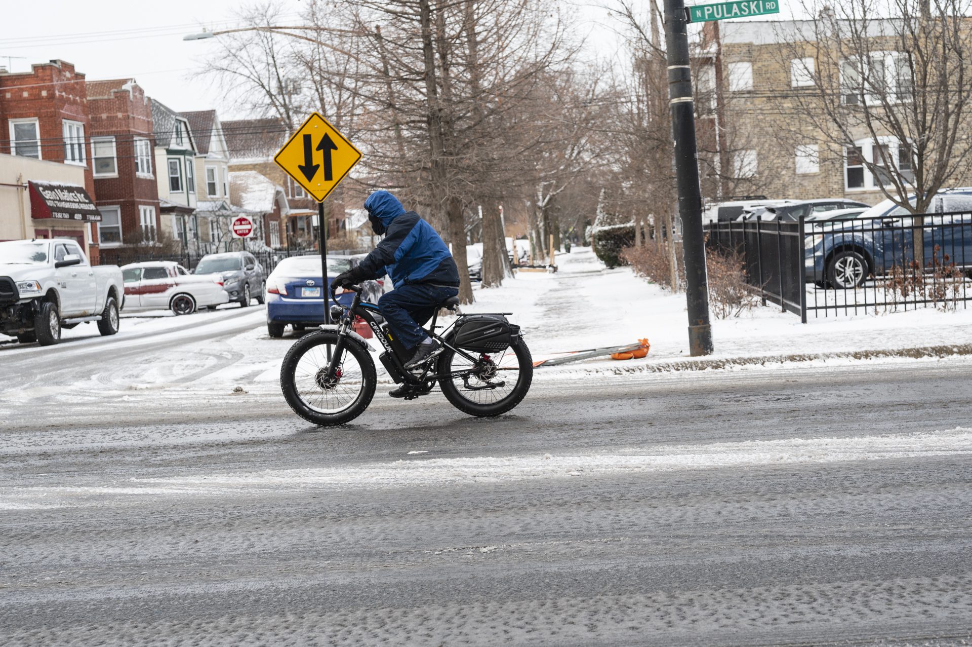 Un ciclista con ropa de invierno baja por Pulaski Road, cubierta de hielo, cuando las temperaturas empiezan a descender por debajo de cero el 14 de enero de 2025.