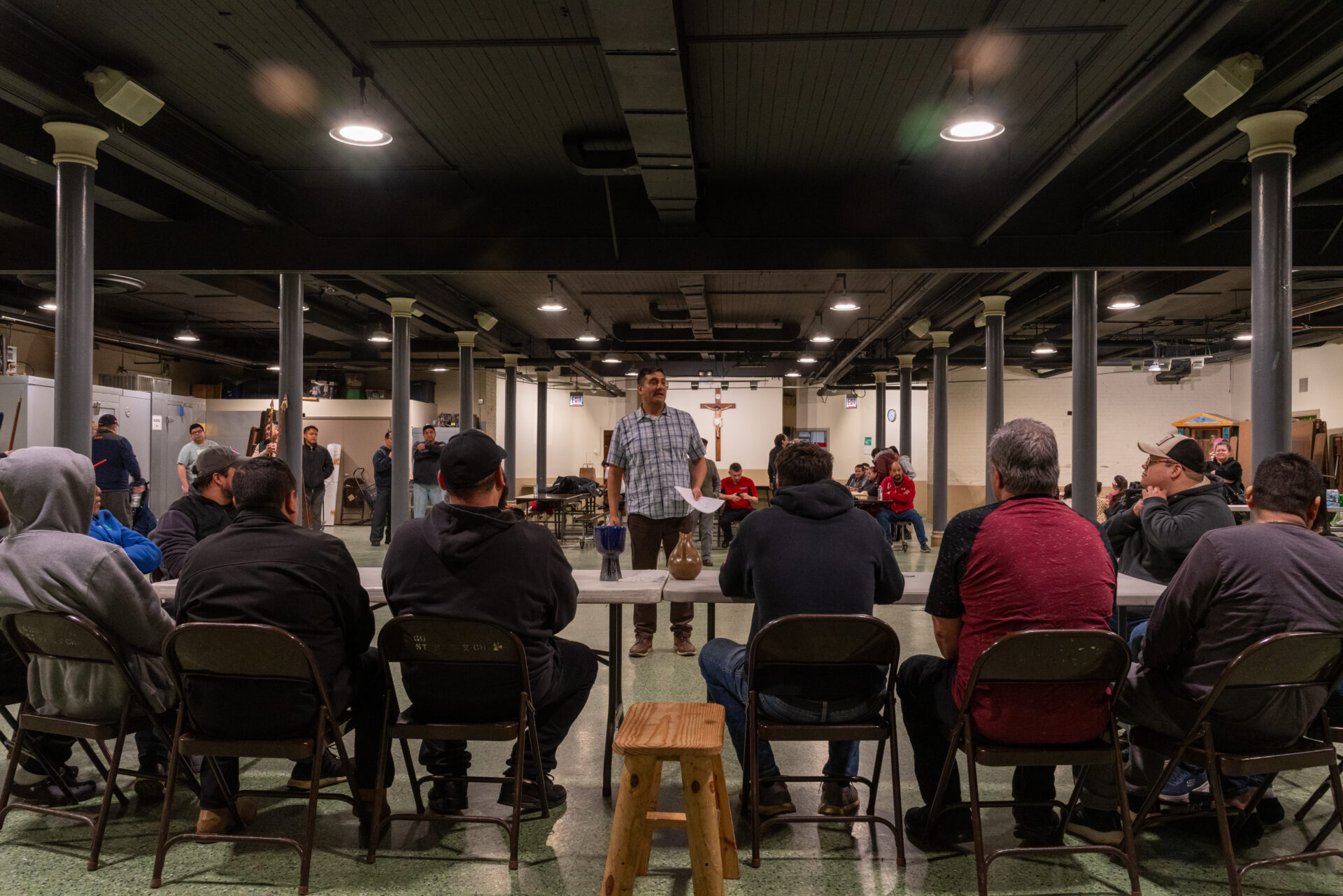 Isaac Barrera, standing, talks to a large group seated actors during a rehearsal for Pilsen’s Via Crucis procession.