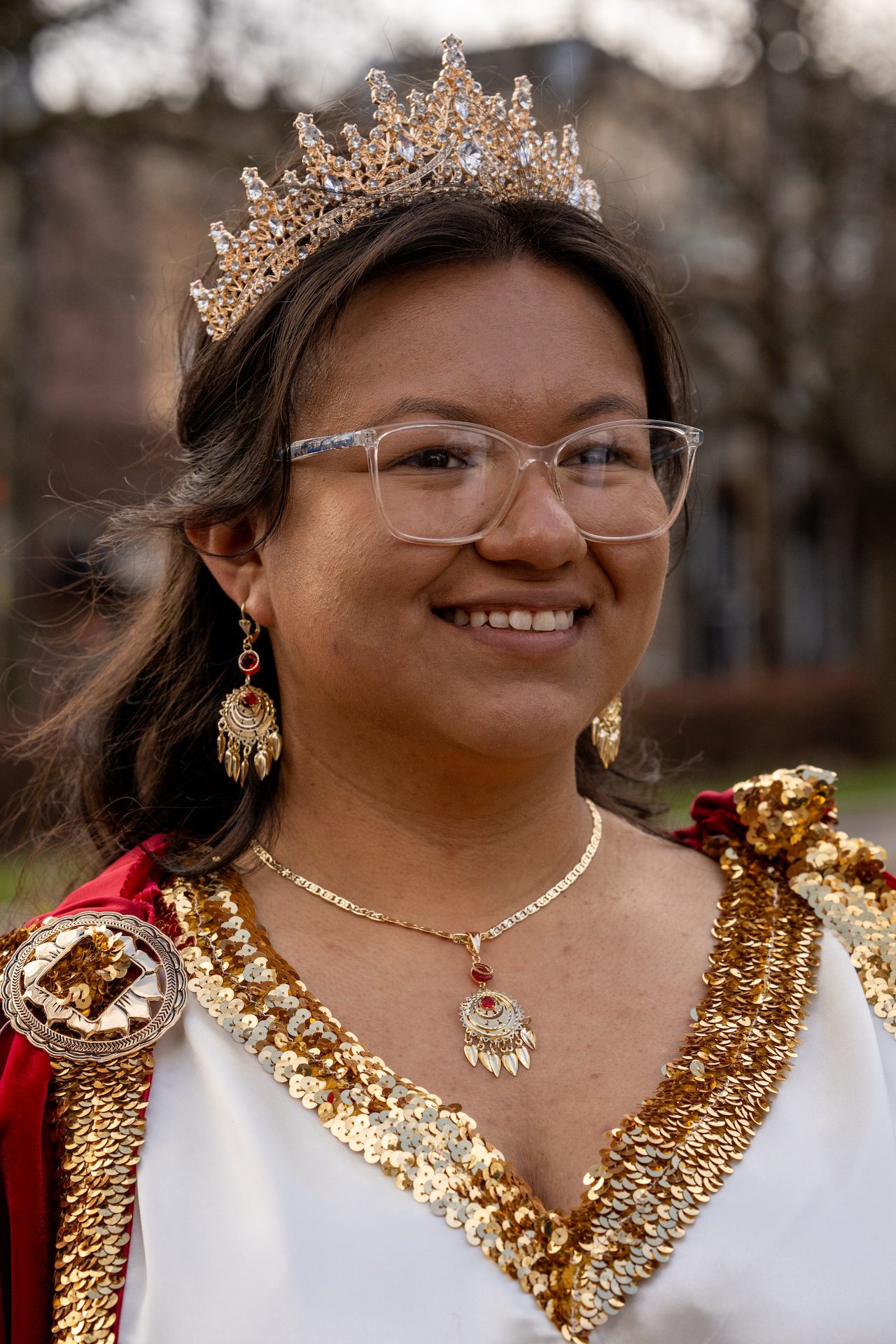Zitlalic Castillo is dressed in a crown and white, red, and gold costume, playing Pontius Pilate's wife at the Via Crucis procession.
