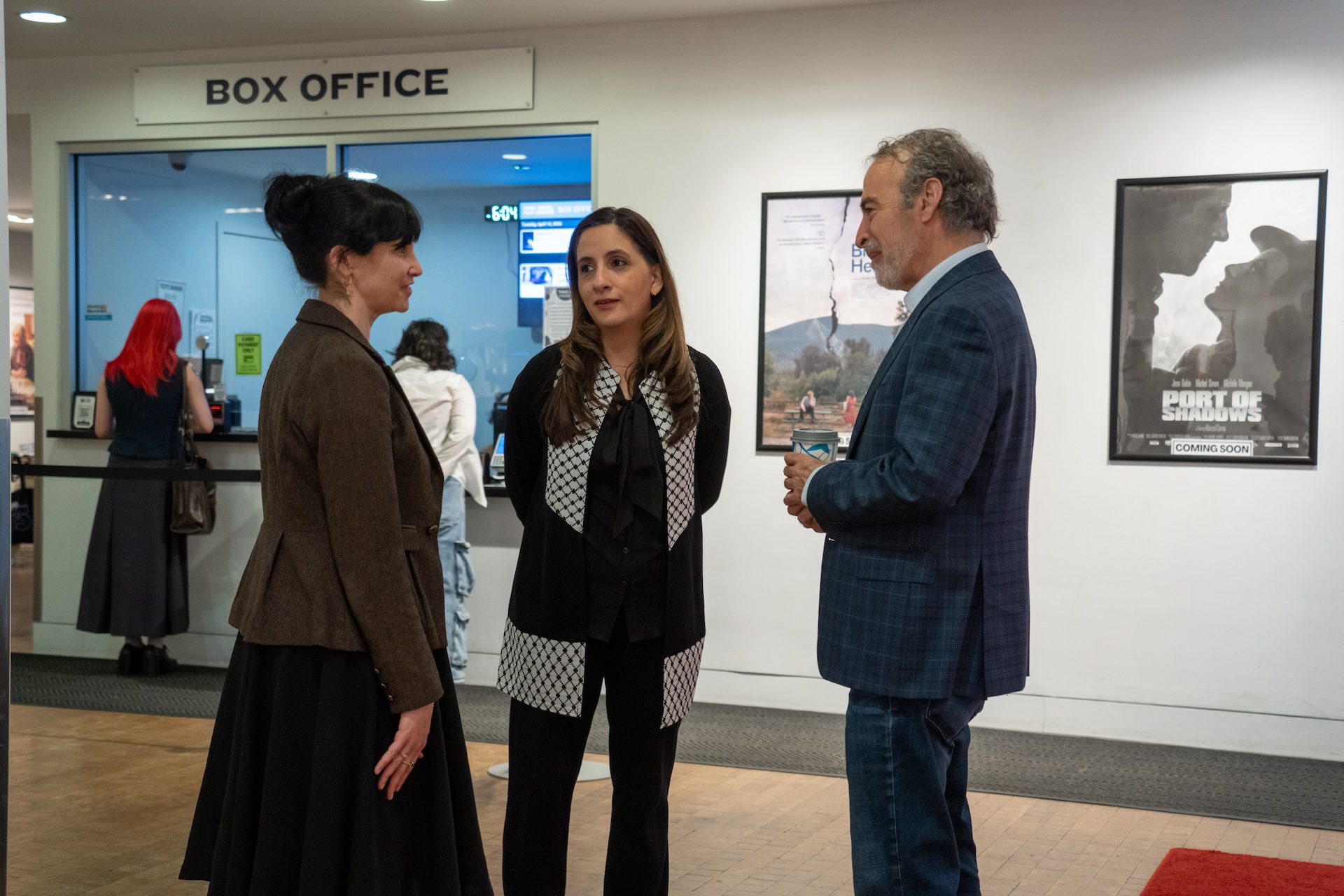 Executive Director Nina Shoman-Dajani talks with two festival attendees in the theater lobby.