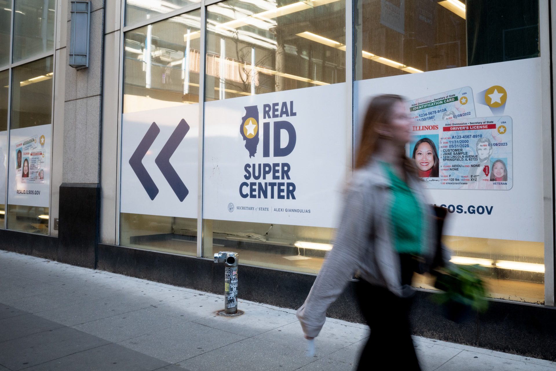 Real ID signage covers an office building as a woman walks past.