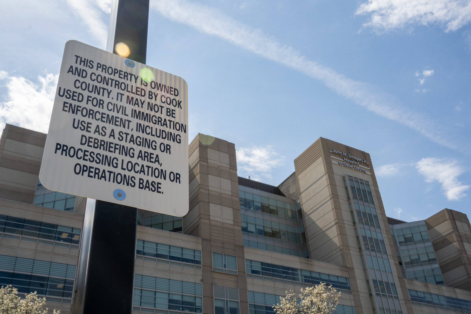 A sign stating limits of immigration enforcement is posted on a light pole near Stroger Hospital.