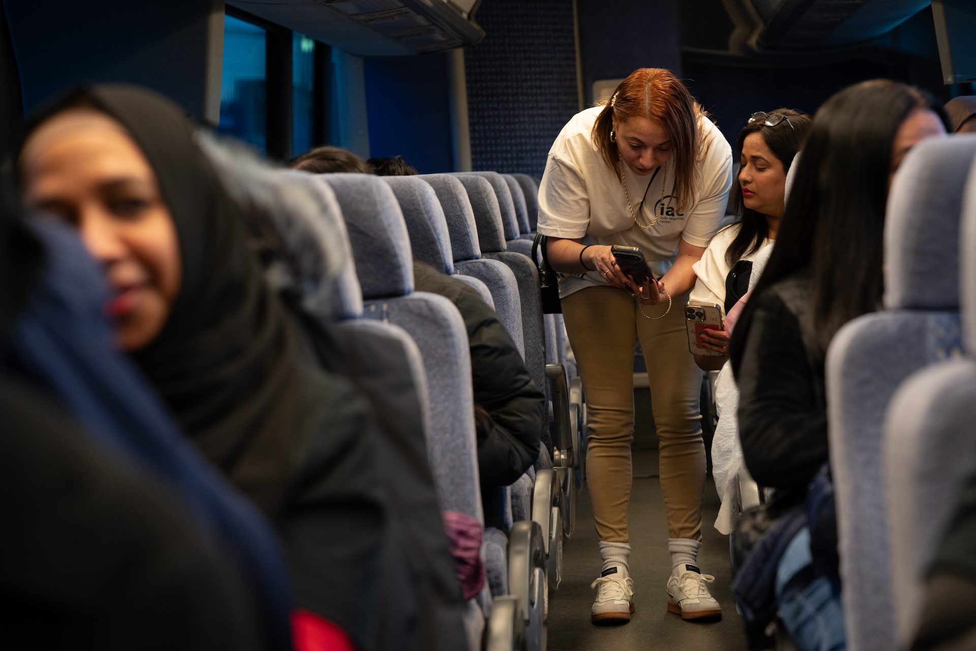 Las voluntarias del Indo American Center, Melanie Ramos (izquierda) y Sonam Mohindra (derecha), miran sus teléfonos celulares para revisar los puntos clave de la política después de abordar el autobús a Springfield el 6 de mayo de 2026.