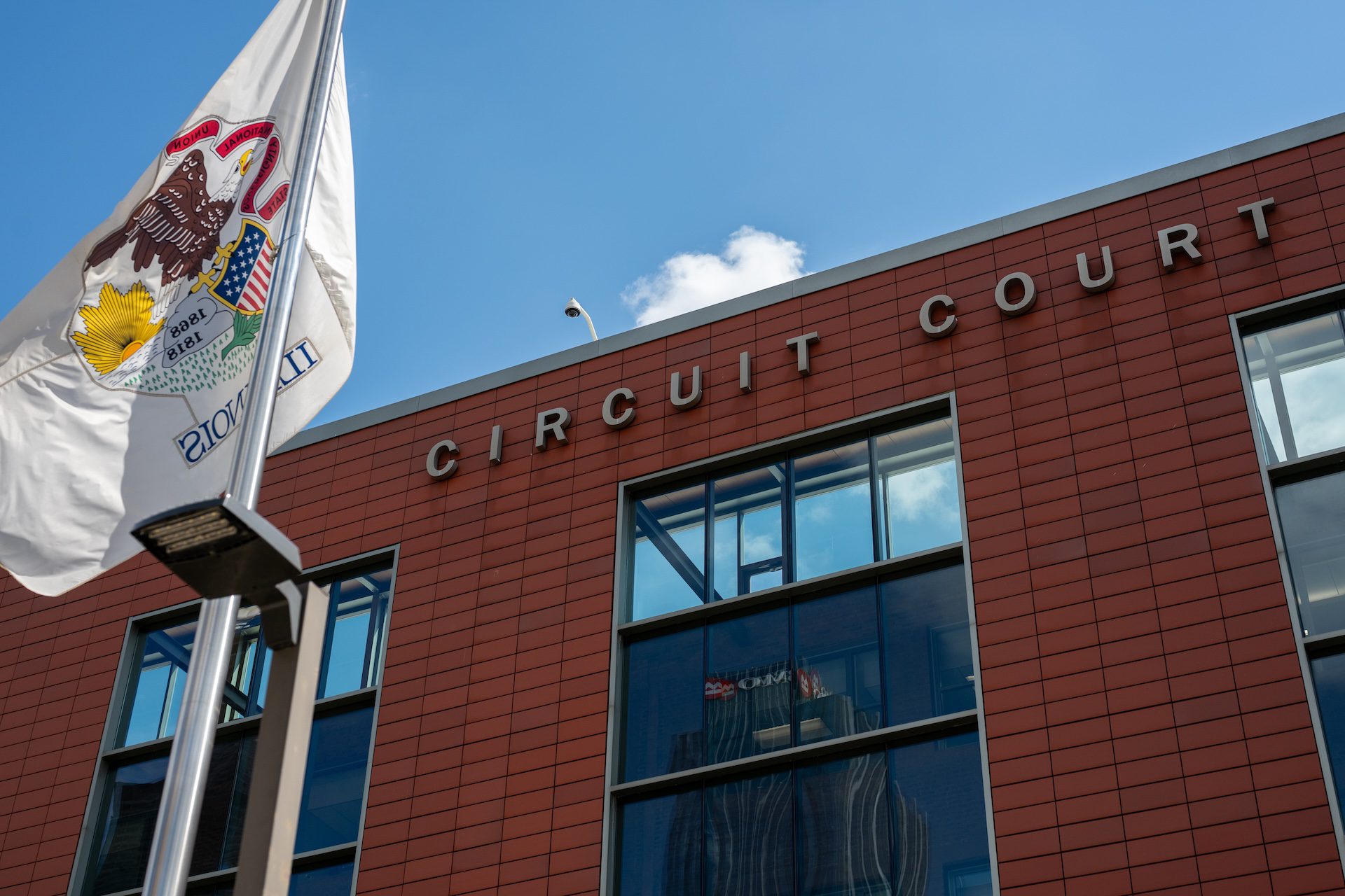 The Illinois flag waves outside the Cook County Domestic Violence Courthouse at 555 W. Harrison. A man was tased and detained after appearing in court by federal agents less than a block away at the CTA Clinton Blue Line station, according to Katie Pelech with the Cook County Public Defenders Office.