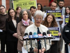 Fred Tsao with the Illinois Coalition for Immigrant and Refugee Rights (ICIRR) stands in front of a large group of advocates outside the Cook County Domestic Violence Courthouse during a press conference.