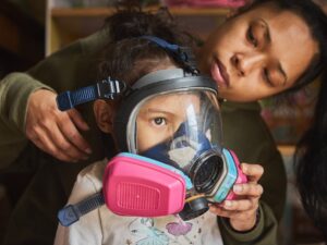 Mindan Ocon puts a gas mask on her daughter, Angelise Ocon, 3, at their family home in Portland, Oregon, on March 9. Protests at the Immigration and Customs Enforcement facility have turned the street outside Ocon’s affordable housing complex into a battlefield of stinging smoke and pepper spray. Ocon has relied on air purifiers and taking her daughter into the bathroom to hide from tear gas, and she’s prepared to use gas masks given to her by community members if it gets worse.