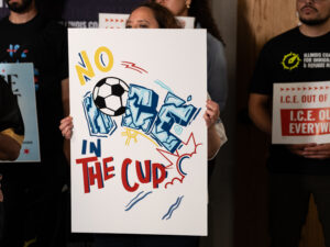 Activistas de diferentes organizaciones sostienen carteles pidiendo que ICE se mantenga alejado de los eventos de la Copa del Mundo.