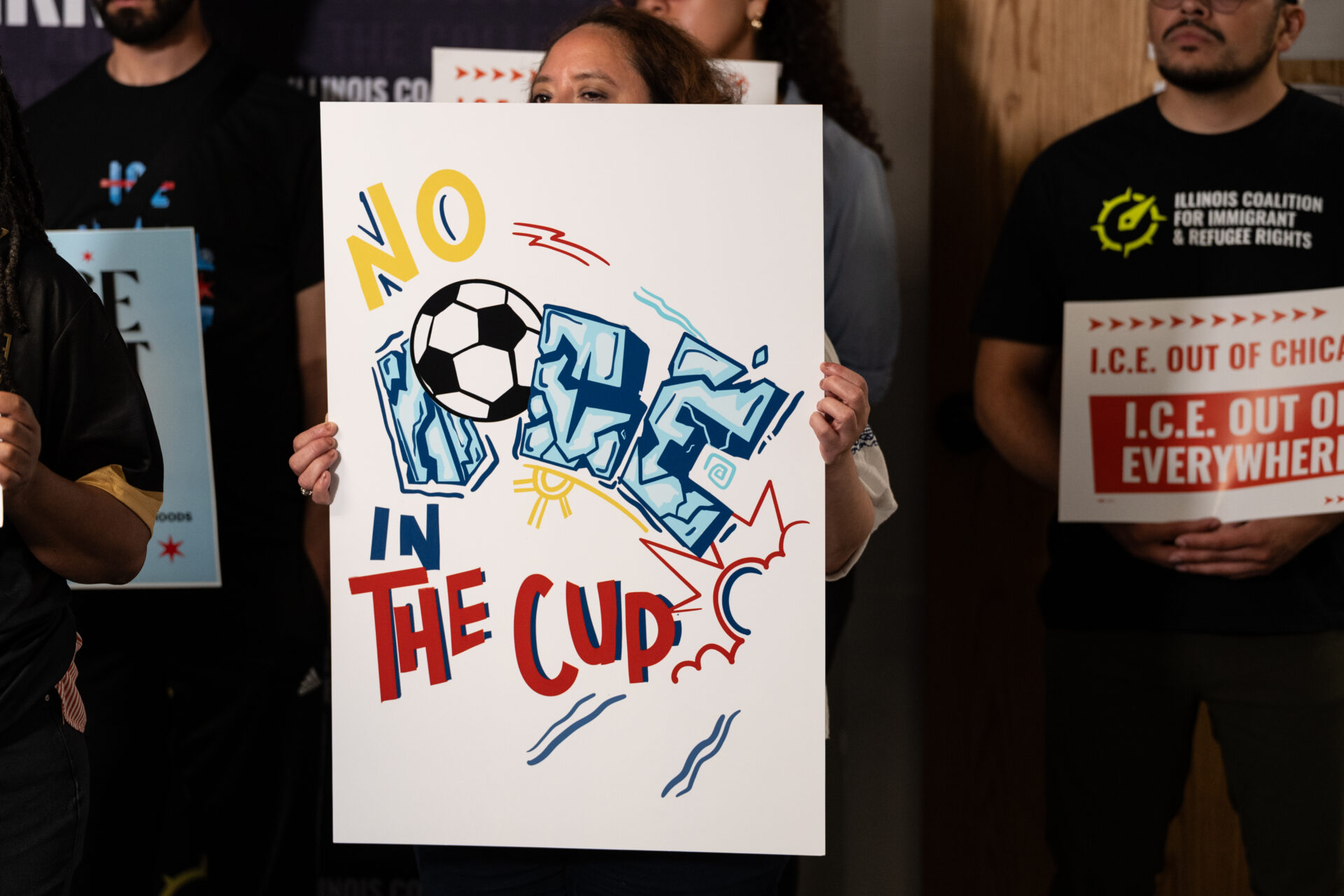 Activistas de diferentes organizaciones sostienen carteles pidiendo que ICE se mantenga alejado de los eventos de la Copa del Mundo.