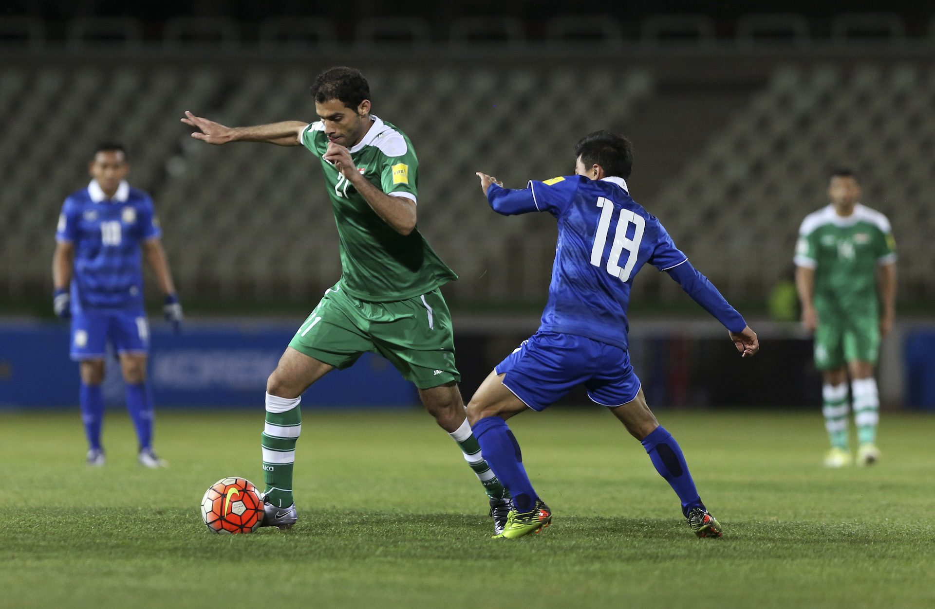 El jugador de la selección nacional de fútbol de Iraq, Saad Abdulameer, vistiendo un uniforme verde, intenta pasar a Chanathip Songkrasin de Tailandia, vistiendo azul, durante su partido en el Estadio Dastgerdi en Teherán, Irán, el jueves 24 de marzo de 2016.
