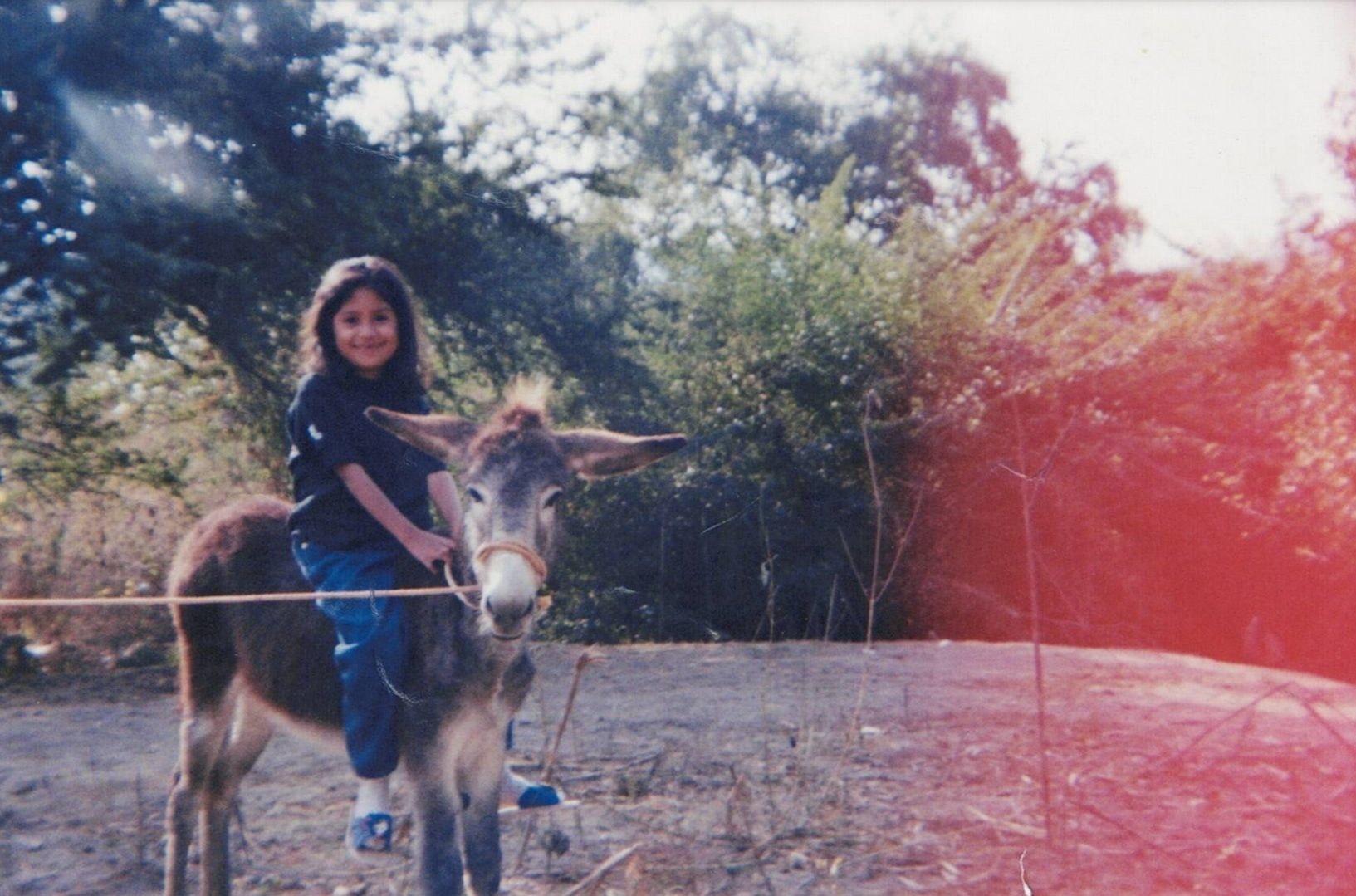 Rocío Villalva sonríe mientras está sentada en un burro en Morelos, México, días antes de que su familia se fuera a Estados Unidos.