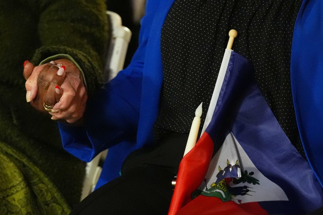 Two people hold hands and a Haitian flag during a vigil at the Little Haiti Cultural Complex after a federal judge blocked the Trump administration from ending temporary immigration status, or TPS, for Haitians on Feb. 3, 2026, in North Miami. As of Thursday, June 25, the Supreme Court ruled to end TPS protections for Haitian and Syrian refugees.