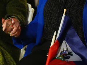 Two people hold hands and a Haitian flag during a vigil at the Little Haiti Cultural Complex after a federal judge blocked the Trump administration from ending temporary immigration status, or TPS, for Haitians on Feb. 3, 2026, in North Miami. As of Thursday, June 25, the Supreme Court ruled to end TPS protections for Haitian and Syrian refugees.