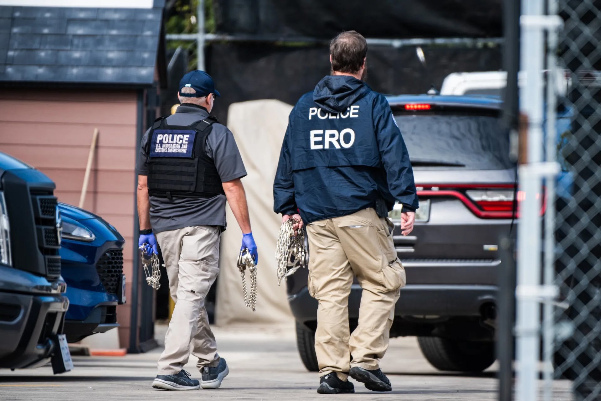 Federal agents walk towards the paring lot of the Broadview facility carrying shackles.