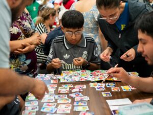 Anthony Cahuatijo, de 13 años, está rodeado de adultos alrededor de una mesa mientras clasifica sus nuevas calcomanías por país antes de pegarlas en su álbum de Panini durante el evento de intercambio de Panini celebrado en la sucursal de la biblioteca de Logan Square el domingo 28 de junio de 2026.