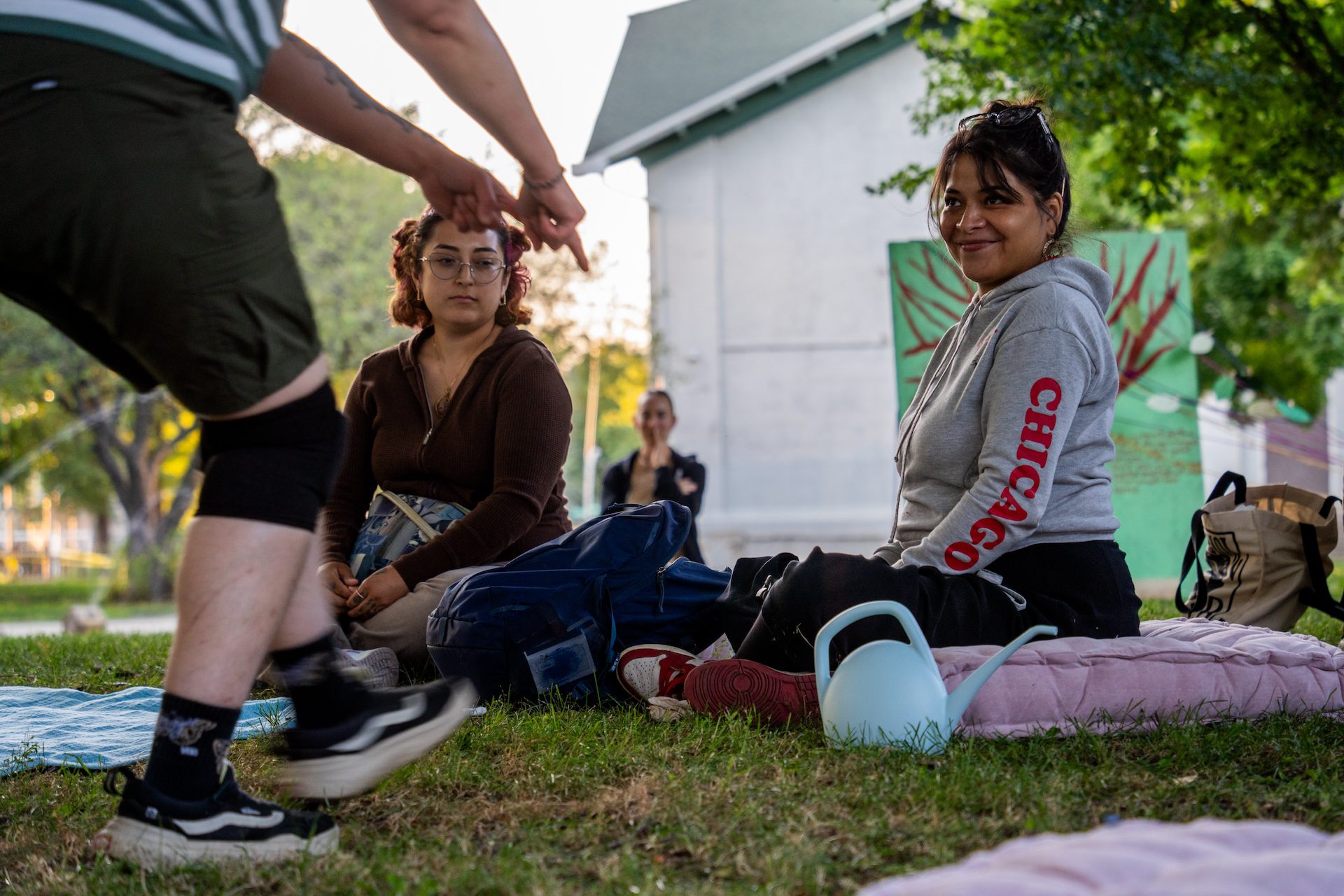Actor Dre Meza, playing “Acorn” interacts with a seated audience member who smiled during Free Street's debut "Touch Grass" performance at Davis Square Park in the Back of the Yards neighborhood on July 22, 2026.