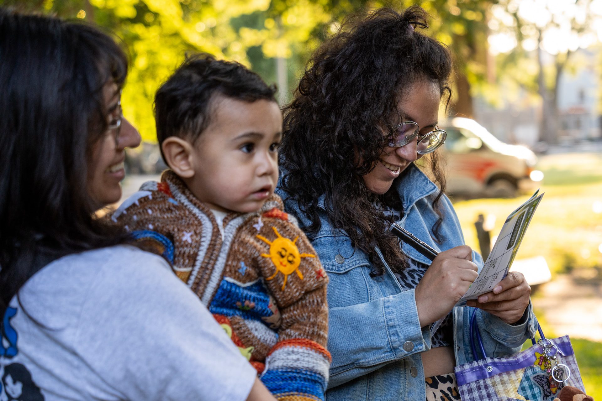 Marcela Ramirez smiles as she writes down a secret for the “gossip tree” art installation after watching Free Street's debut "Touch Grass" performance at Davis Square Park.