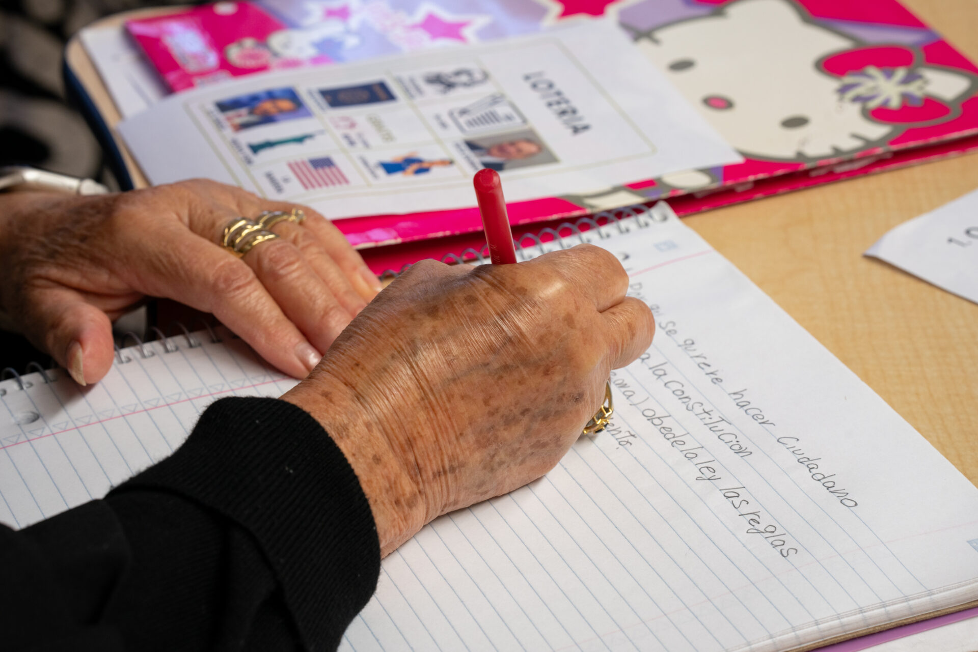 A close-up on Celia Salamanca's hands as she takes notes during her Spanish-language citizenship class at Erie House.