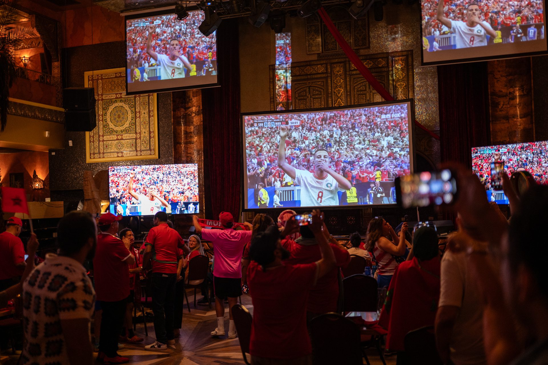 Fans celebrate in front of five large screen TVs after Morocco scored their first goal against Canada during a World Cup viewing event at Alhambra Palace in the West Loop.