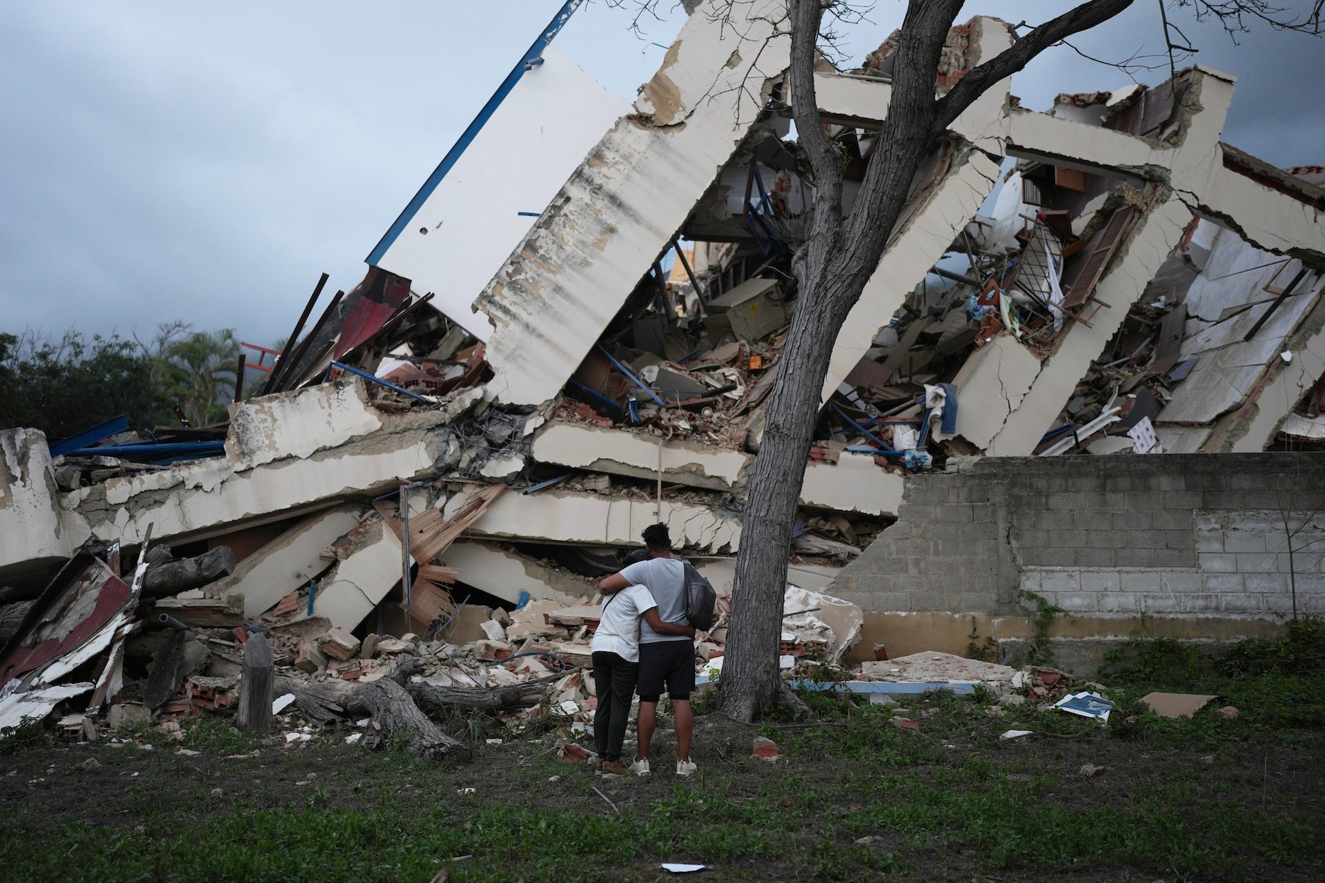 Una pareja se abraza frente a un edificio destruido por dos terremotos tres días después de que azotaran La Guaira, Venezuela.