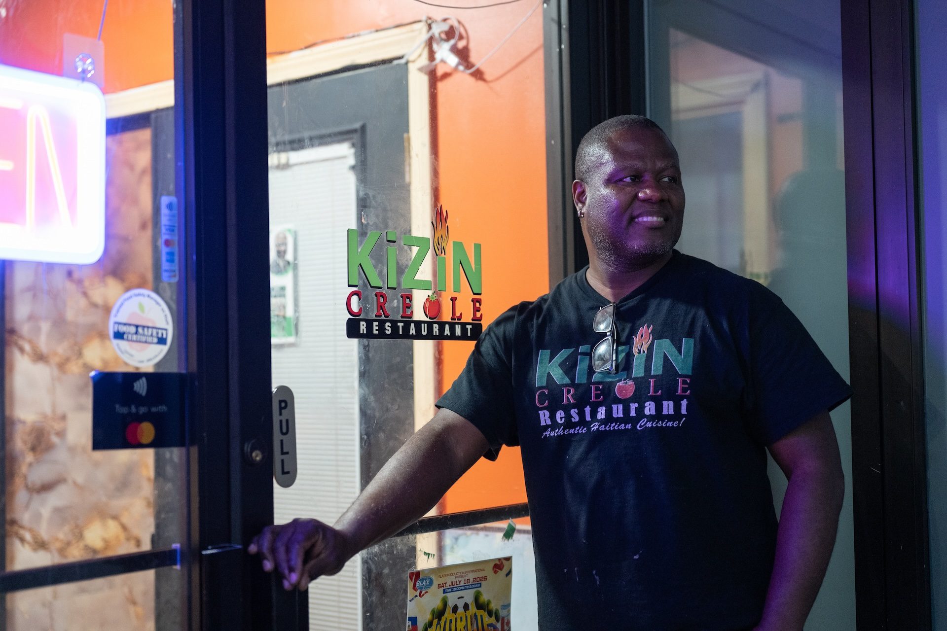Daniel Desir, owner of Kinzin Creole restaurant in West Ridge, stands outside his establishment wearing a t-shirt with a Kinzin Creole logo.