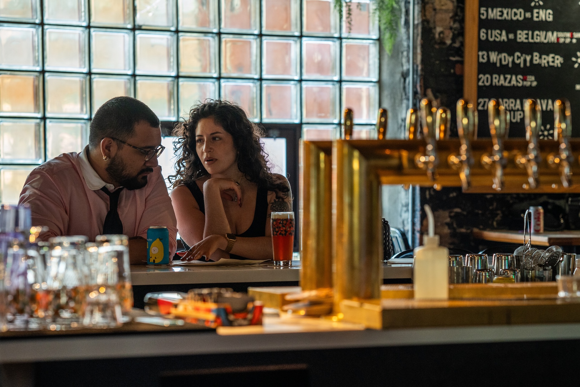 A couple talks at a bar over drinks at Marz’s Mothership location offers in an industrial space above their brewing tanks.