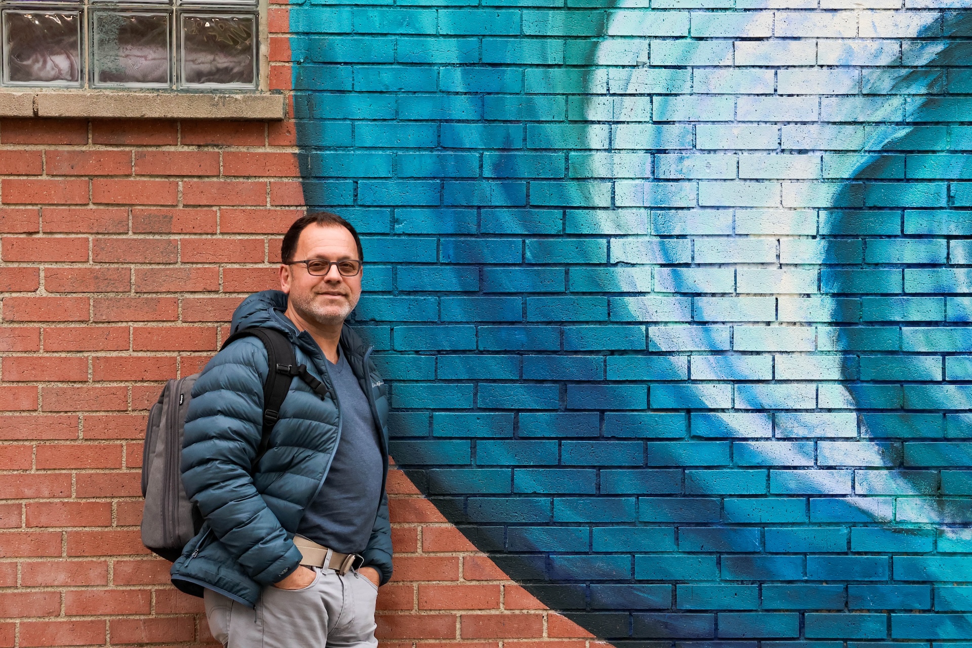 Luciano Pedota, who leads the Illinois Venezuelan Alliance, leans against a colorful mural in Chicago.