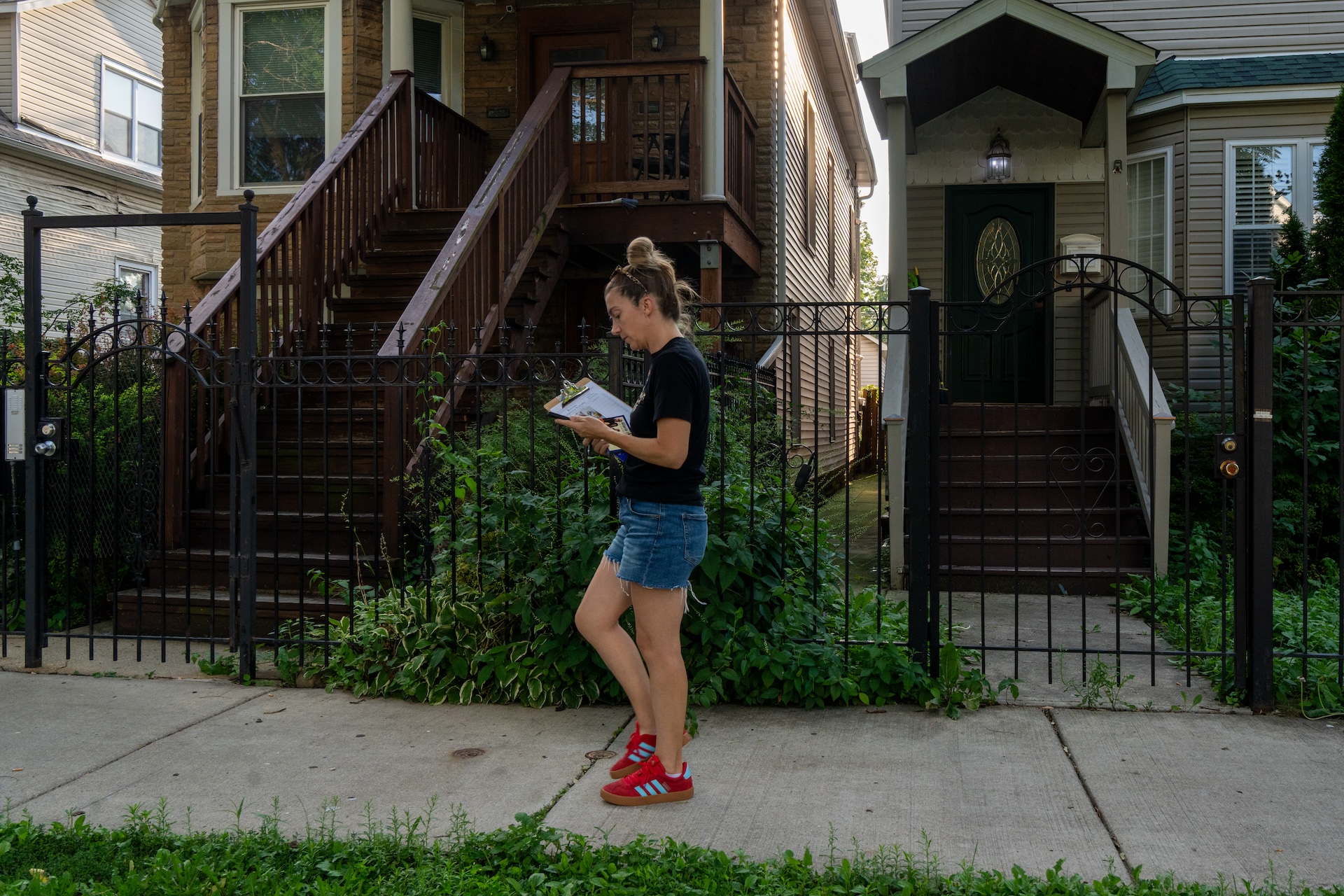 Christine Dussault stands in front of homes as she updates her route on a canvassing app after successfully speaking to residents in her neighborhood of Albany Park on August 4, 2026.