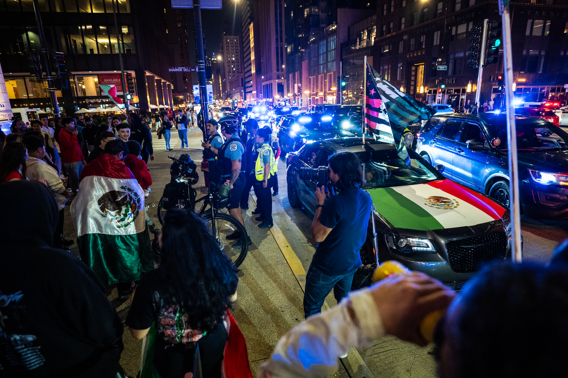 Chicago police officers pull over a car with a flag attached to a pole through its sunroof as a few dozen celebrate Mexican Independence Day in the Loop.