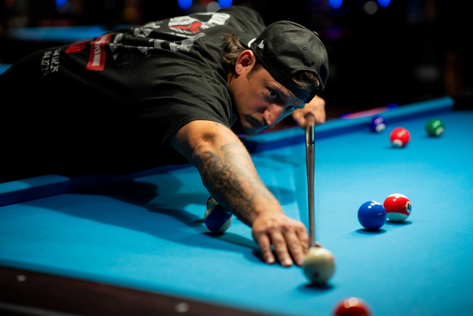 Brian Kamer leans over a pool table as he lines up a bank shot while playing a solo game at Nick’s Billiards Academy.